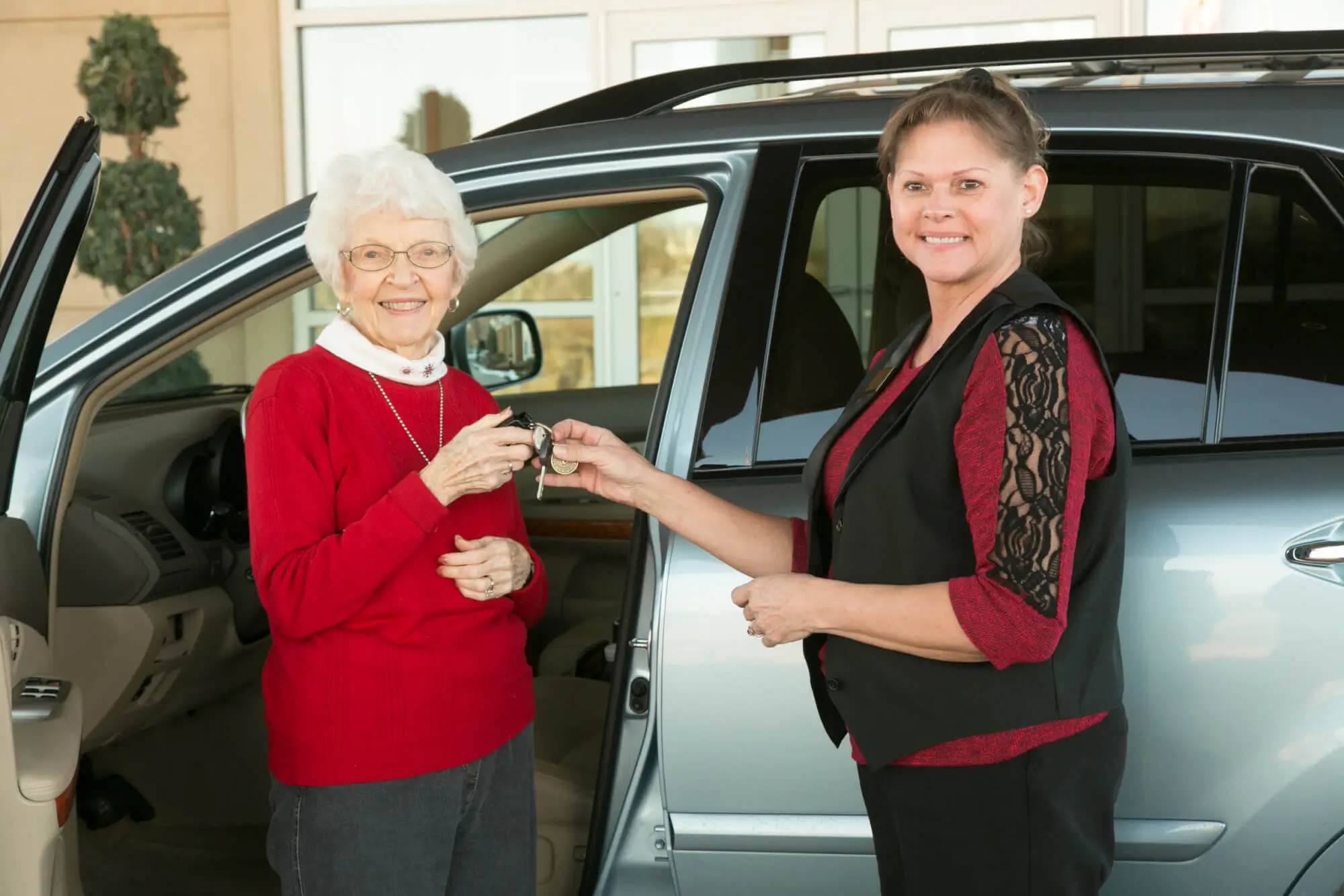 Young woman giving keys to RLC resident in front of car
